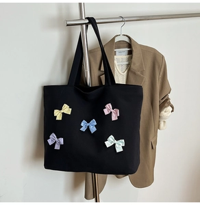 Detail of black waffle texture tote bag featuring colorful polka dot bows and spacious interior