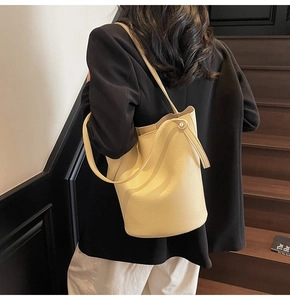 Detail view of yellow lychee grain leather bucket bag with vertical strap design