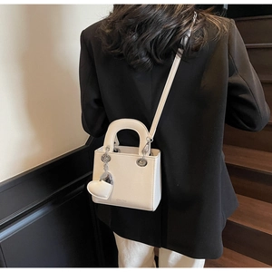 Detailed shot of white lychee texture handbag with heart charm on a model