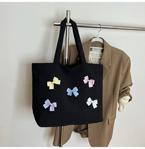 Close-up of black waffle fabric tote bag featuring colorful polka dot bow details