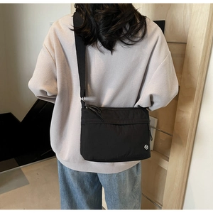 Detail of minimalist black crossbody tote bag with wide strap on casual model