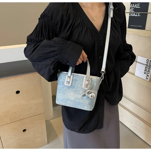 Detail of light blue denim mini bucket bag with silver trim and metallic balloon dog charm