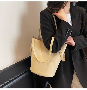 Detail of minimalist cream leather tote bag with pebble grain texture on model
