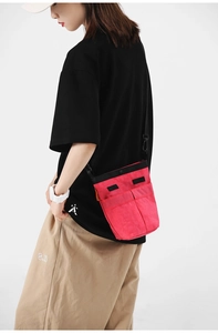 Dettaglio della borsa a tracolla in nylon rosa rosso con doppie tasche frontali e tracolle