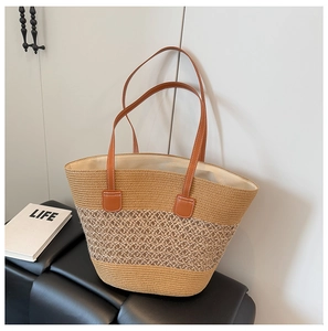 Detalle de bolso tote de paja trenzada con asas de cuero marrón y costuras blancas en contraste
