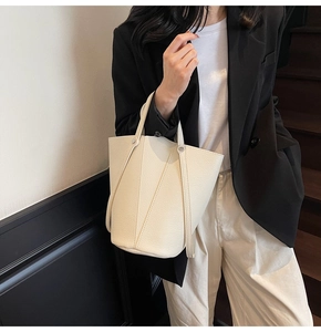 Close-up of off-white lychee grain leather tote with silver rivet details and strap
