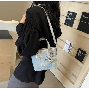 Detail of light blue denim mini bucket bag with silver handles and balloon dog charm