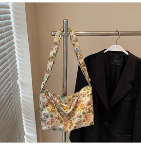 Detail of off-white tote bag with 3D floral and bear decorations on a wide strap