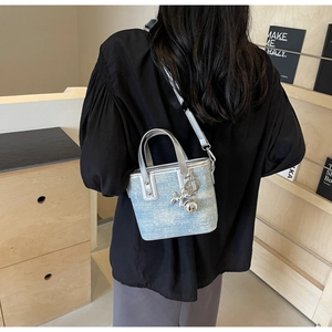 Detail of light blue denim bucket bag with silver leather trim and balloon dog charm
