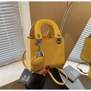 Detail of yellow lychee leather mini handbag with heart charm and slim shoulder strap
