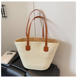 Detalle de bolso tote de paja tejida con asas de cuero sintético marrón y costuras reforzadas