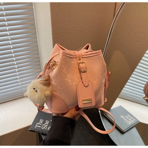 Pink faux snake texture bucket bag detail with plush toy charm and gold buckle