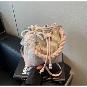 Detail of straw woven bucket bag featuring pink leather trim and lace bow accent