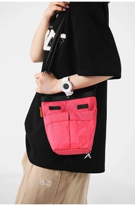 Dettaglio della borsa a tracolla in nylon rosa con doppie tasche frontali e tracolle nere