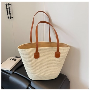 Detalle del bolso de paja trenzada con correas de cuero marrón y costuras resistentes