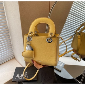 Detailed view of yellow lychee leather mini bag with silver metal ring handle connectors