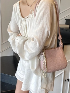 Pink lychee texture bucket bag with tennis racket charm worn by model on shoulder