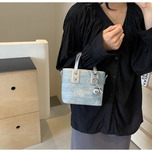 Detail view of blue denim mini tote bag with silver handle and metallic ball charm