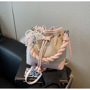 Detail of pink woven bucket bag with lace trim, pearl beads, and a heart charm