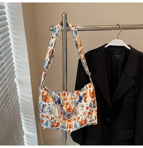 Detailed close-up of a white tote bag with colorful forest animal prints on a metal rack
