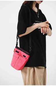 Dettaglio della borsa a tracolla in nylon rosa con design multitasche e cinghie a contrasto