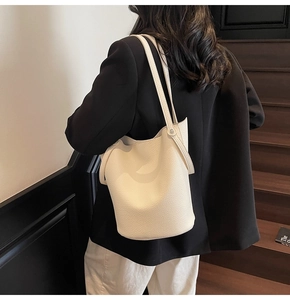 Detail of creamy white litchi grain leather bucket bag with premium texture and strap