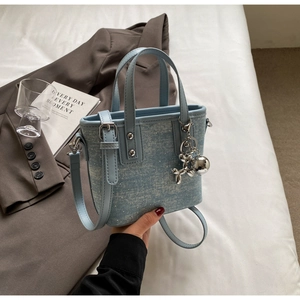 Detail of light blue denim textured bucket bag with sequins and balloon dog charm