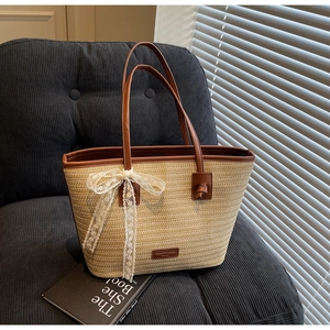 Détail du sac cabas en paille tissée avec bordure en cuir marun et élégant nœud en dentelle
