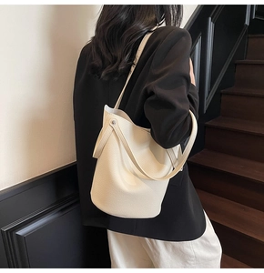 Chic off-white bucket bag in lychee pattern leather shown from a side-back view