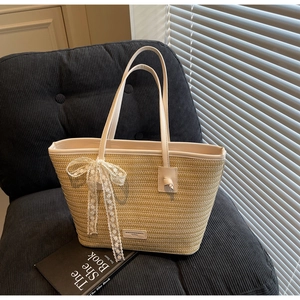Gros plan d'un sac cabas en paille tissée avec nœud en dentelle blanche et cuir chic