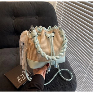 Detail of woven straw bucket bag with mint green leather trim and pearl lace charm