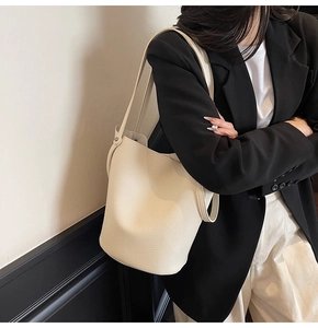 Detail of creamy white pebble leather bucket bag showing soft texture and shoulder strap