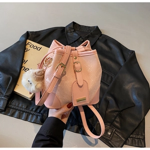 Detail of pink snake skin texture bucket bag with gold hardware and plush charm