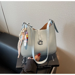 Detail of light blue bucket bag with silver G-buckle and colorful smiley face charm