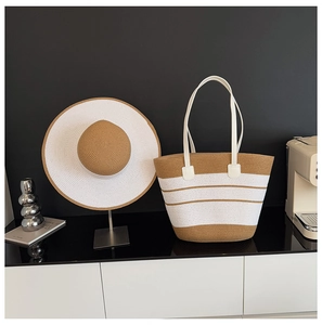 Détail du chapeau de paille d'été et du sac de plage rayé avec des poignées en cuir blanc