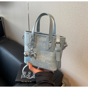Detailed macro view of light blue denim tote bag with shiny rhinestones and silver hardware