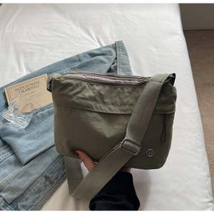 Detail showing the adjustable nylon shoulder strap and silver metal buckle on the green bag
