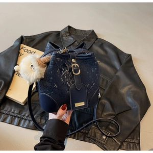 Detail of dark blue bucket bag with snake-skin texture and white plush charm