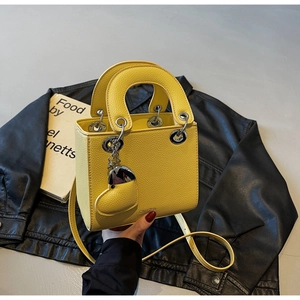 Detail of yellow litchi texture handbag with heart charm and silver hardware