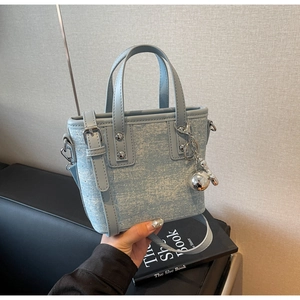 Detail of light blue denim texture tote bag with silver studs and metal charms