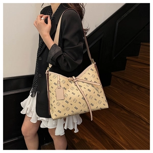 Side view of beige hobo bag with teddy bear print on a model in an indoor setting