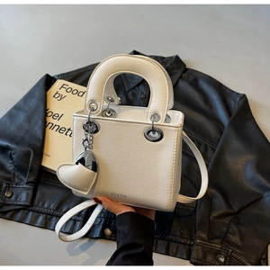 Detailed macro view of white pebble leather texture and metallic hardware on lady tote bag