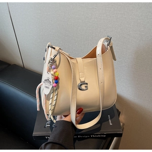 Detail of hobo bag with silver G-buckle, leather texture, and colorful beaded charm