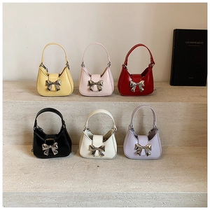 Vue détaillée de mini sacs à main avec nœud en six couleurs sur des marches en pierre