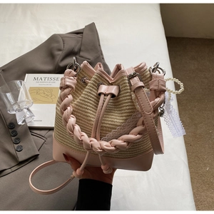 Detailed shot of woven bucket bag featuring pink leather trim and white lace accents