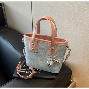 Detail of blue denim bucket bag with pink leather straps, rivets and balloon dog charm