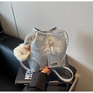 Macro detail of silver snake-pattern bucket bag with metallic luster and plush charm