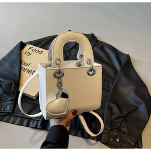 Close-up of white pebble leather mini handbag with heart charm and silver metal hardware