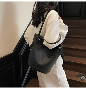 Close-up of black litchi pattern leather bucket bag with wide shoulder strap details