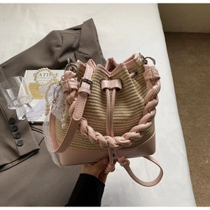 Close-up of pink leather and woven straw bucket bag with pearl chain and lace details